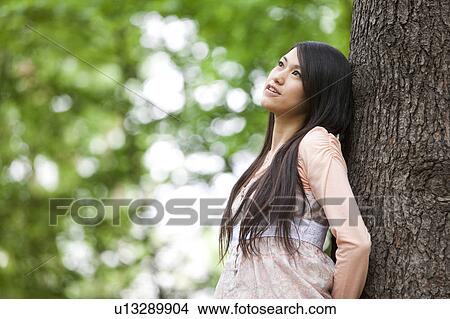 Young woman leaning on tree View Large Photo Image Picture - Young woman leaning on tree. Fotosearch