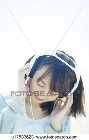 Stock Image - Young Woman Listening to Headphones. Fotosearch