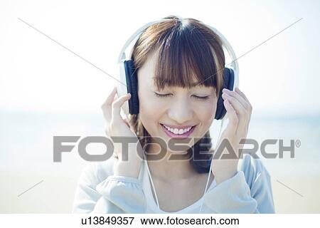 Stock Photo - Young Woman Listening to Headphones. Fotosearch