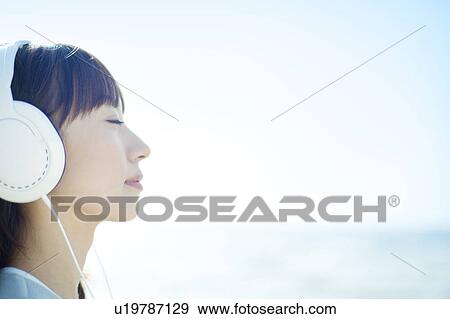 Stock Photo - Young Woman Listening to Headphones. Fotosearch