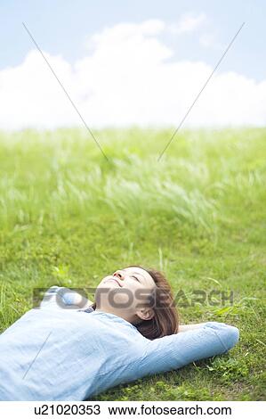 Stock Image - Young Woman Relaxing on Grass. Fotosearch