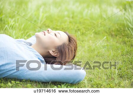 Stock Photograph - Young Woman Relaxing on Grass. Fotosearch