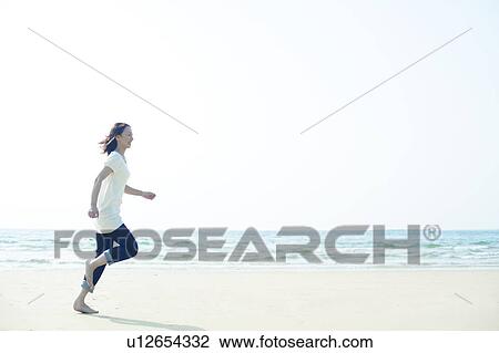 Stock Image - Young Woman Running on Beach. Fotosearch
