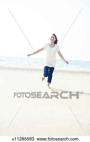 Stock Image - Young Woman Running on Sea. Fotosearch