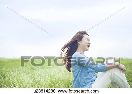 Stock Photo - Young Woman Sitting on Tall Grass. Fotosearch
