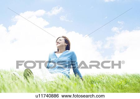 Stock Photograph - Young Woman Sitting on Tall Grass. Fotosearch