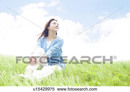 Stock Photography - Young Woman Sitting on Tall Grass. Fotosearch