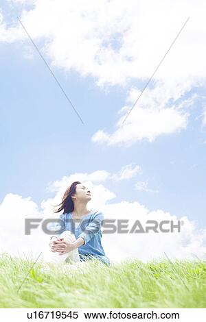 Stock Photography - Young Woman Sitting on Tall Grass. Fotosearch