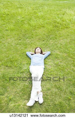 Stock Image - Young Woman Sleeping on Grass. Fotosearch