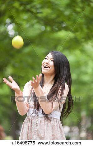 Stock Photography - Young woman throwing an apple . Fotosearch