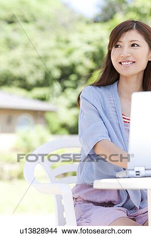 Picture - Young Woman Using Laptop in Garden. Fotosearch