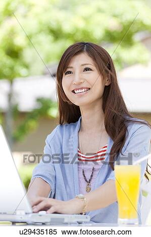 Stock Photography - Young Woman Using Laptop in Garden. Fotosearch