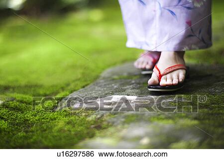Stock Photograph - Young Woman Wearing Sandals Standing on Stone. Fotosearch
