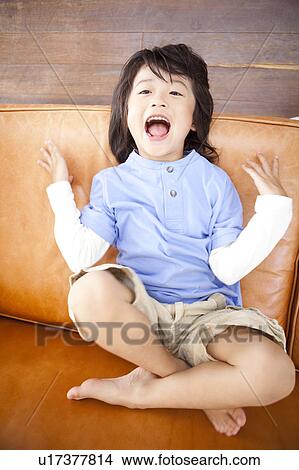 A boy sitting on couch View Large Photo Image Picture - A boy sitting on couch. Fotosearch
