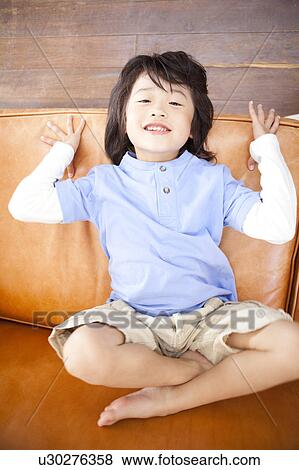 Stock Photo - A boy sitting on couch. Fotosearch