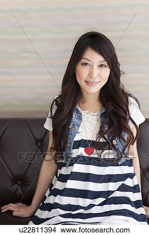 A young woman sitting on couch View Large Photo Image Picture - A young woman sitting on couch. Fotosearch