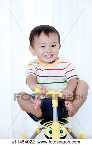 Stock Image - Baby Boy Playing with Tricycle. Fotosearch