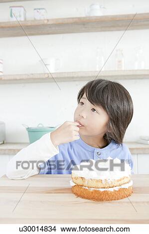 Picture - Boy licking an icing on his finger, Hyogo Prefecture, Honshu, Japan. Fotosearch