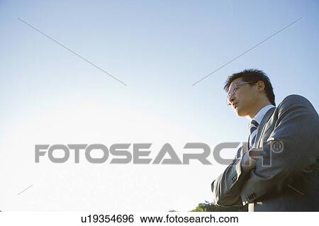 Stock Photograph - Businessman Against Sky, Low Angle View. Fotosearch
