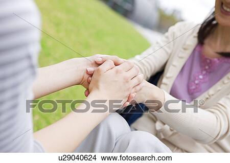 Picture - Caretaker and mature woman on wheelchair holding hands. Fotosearch