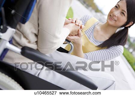 Caretaker and mature woman on wheelchair holding hands View Large Photo Image Stock Photo - Caretaker and mature woman on wheelchair holding hands. Fotosearch