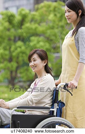 Caretaker pushing mature woman on wheelchair View Large Photo Image Stock Image - Caretaker pushing mature woman on wheelchair. Fotosearch