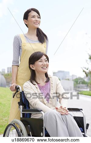 Caretaker pushing mature woman on wheelchair View Large Photo Image Stock Image - Caretaker pushing mature woman on wheelchair. Fotosearch