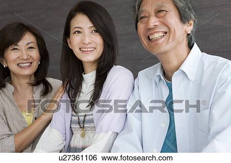 Stock Photograph - Family sitting on sofa. Fotosearch
