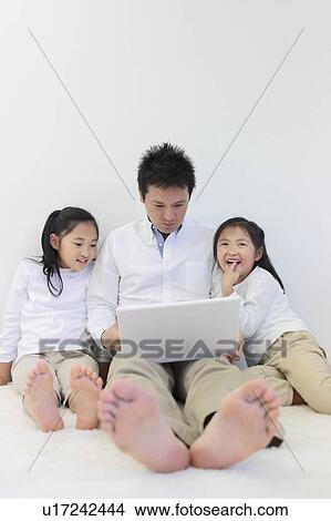Picture - Father and Two Daughters Using Laptop. Fotosearch