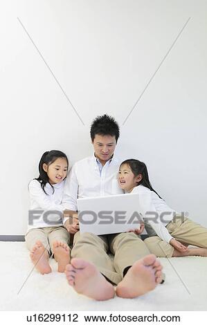 Stock Image - Father and Two Daughters Using Laptop. Fotosearch