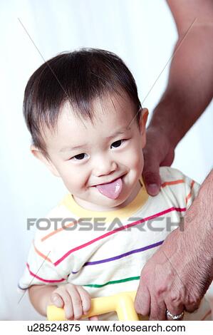 Stock Photography - Father Holding Baby Boy Who Is Sticking Out Tongue. Fotosearch