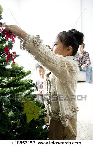 Stock Image - Girl Decorating Christmas Tree. Fotosearch