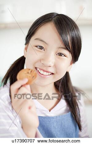 Stock Photo - Girl eating a cookie, Hyogo Prefecture, Honshu, Japan. Fotosearch