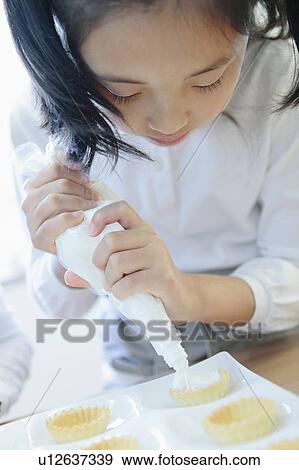 Girl Squeezing Cream Onto Cakes View Large Photo Image Stock Photo - Girl Squeezing Cream Onto Cakes. Fotosearch