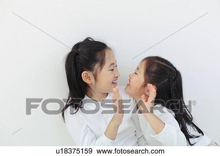 Stock Photo - Girls Looking At Each Other and Smiling. Fotosearch