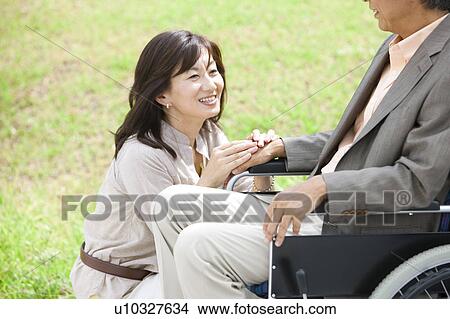 Mature woman and senior man on wheelchair holding hands View Large Photo Image Picture - Mature woman and senior man on wheelchair holding hands. Fotosearch