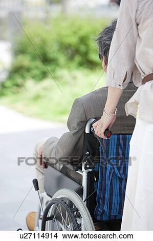 Mature woman pushing senior man on wheelchair View Large Photo Image Picture - Mature woman pushing senior man on wheelchair. Fotosearch