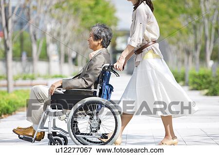 Mature woman pushing senior man on wheelchair View Large Photo Image Stock Photo - Mature woman pushing senior man on wheelchair. Fotosearch