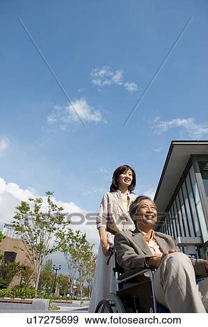 Mature woman pushing senior man on wheelchair View Large Photo Image Stock Photo - Mature woman pushing senior man on wheelchair. Fotosearch