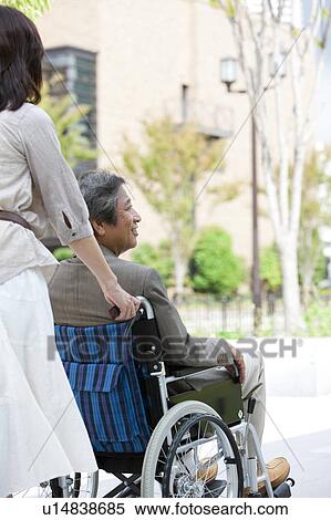 Stock Photography - Mature woman pushing senior man on wheelchair. Fotosearch