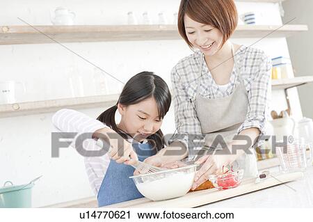 Stock Image - Mother and daughter in kitchen baking, Hyogo Prefecture, Honshu, Japan. Fotosearch