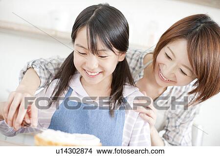Mother and daughter in kitchen decorating cake, Hyogo Prefecture, Honshu, Japan View Large Photo Image Picture - Mother and daughter in kitchen decorating cake, Hyogo Prefecture, Honshu, Japan. Fotosearch