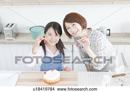 Picture - Mother and daughter in kitchen decorating cake, Hyogo Prefecture, Honshu, Japan. Fotosearch