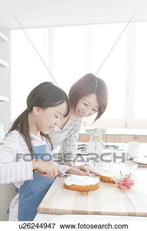 Stock Photo - Mother and daughter in kitchen decorating cake, Hyogo Prefecture, Honshu, Japan. Fotosearch
