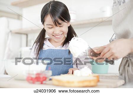 Stock Photograph - Mother and daughter in kitchen decorating cake, Hyogo Prefecture, Honshu, Japan. Fotosearch