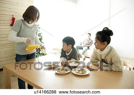 Stock Photo - Mother Pouring Juice for Children. Fotosearch