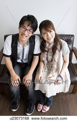 Portrait of young couple sitting on sofa View Large Photo Image Stock Photo - Portrait of young couple sitting on sofa. Fotosearch