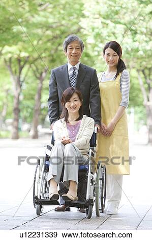 Stock Photo - Senior man with wife in wheelchair and caretaker. Fotosearch