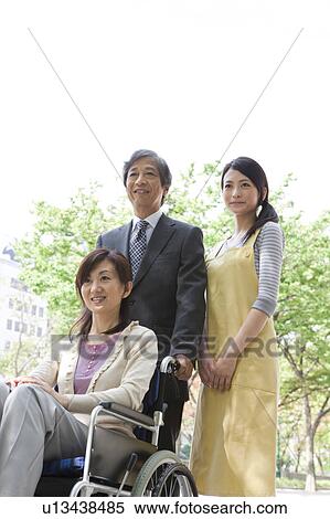 Stock Photography - Senior man with wife in wheelchair and caretaker. Fotosearch