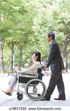 Stock Image - Senior man with wife in wheelchair. Fotosearch